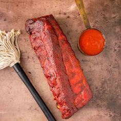 a large piece of meat sitting next to a whisk on top of a table