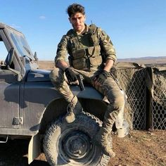 a man sitting on top of a truck in the desert