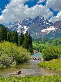 the mountains are covered in snow and green grass, with a stream running between them