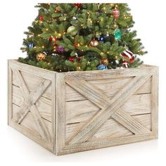 a christmas tree in a wooden box with ornaments on it and a lit up ornament