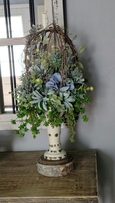 a vase filled with flowers sitting on top of a wooden table next to a mirror