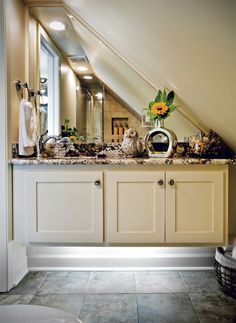 an attic bathroom with white cabinets and marble counter tops, sunflowers on the sink