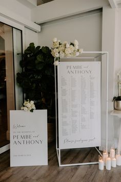 a sign and candles are on the floor in front of a table with an arrangement of flowers