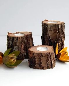 three wooden candles are sitting next to each other with leaves on the side and one candle in the middle