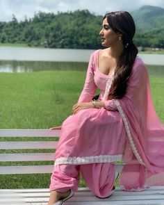 a woman sitting on top of a white bench wearing a pink dress and matching shoes