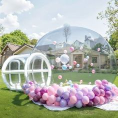 an inflatable bubble with balloons floating on the ground next to a lawn and house