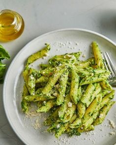 a white plate topped with pasta covered in pesto