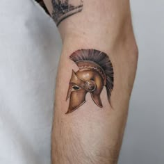 a man's arm with a spartan helmet tattoo on it