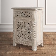 an old wooden cabinet with carvings on the front and sides, against a white wall