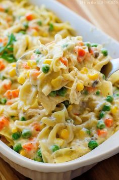 a spoon full of macaroni salad with peas and carrots