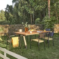 a wooden table sitting on top of a lush green field next to a stone wall