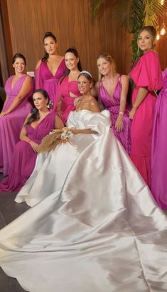 a group of women standing next to each other in pink and white dresses on the floor