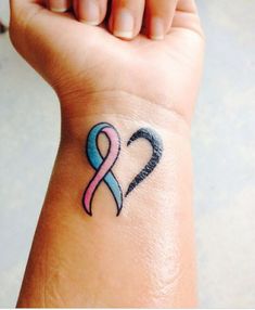 a woman's wrist tattoo with a pink and blue ribbon on the left side