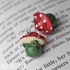 two green and red mushrooms sitting on top of an open book with white polka dots