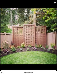 a garden with green grass and flowers next to a wooden privacy fence in the middle of a yard