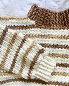 crocheted blanket laying on top of each other with brown and white stripes in the middle