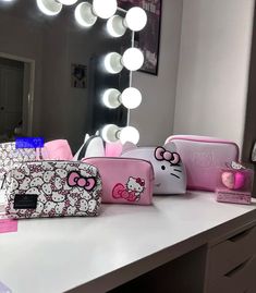 hello kitty makeup bags are on a counter in front of a mirror with the lights turned on