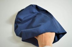 a person's hand is holding up a blue piece of cloth that has been folded over