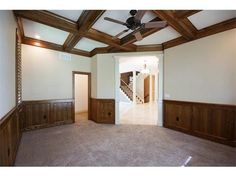 an empty room with wood paneling and ceiling fan