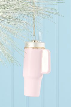 a pink coffee cup ornament hanging from a tree