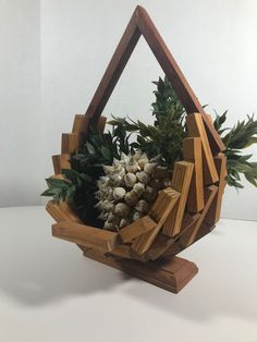 a sculpture made out of wood and pine cones with leaves on top, sitting on a white surface