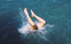 a woman laying on her back in the water with her legs spread out and feet up