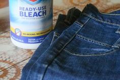 a bottle of bleach sitting on top of a pair of blue jeans next to a pair of denim pants