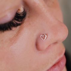 a woman's nose with a tiny heart piercing on it