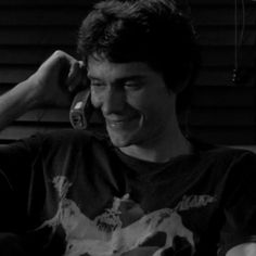 black and white photo of a man smiling with his hand on his head while talking on the phone