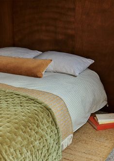 a bed with green bedspread and two pillows on top of the headboard