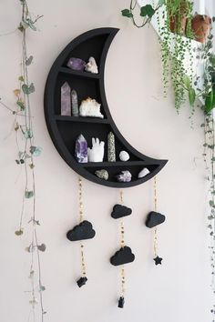 a crescent shaped shelf with rocks hanging from it's sides and a moon on the wall