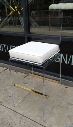 a white chair sitting on top of a sidewalk next to a store front window,