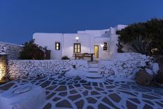 a white house with stone walls and steps leading up to the front door at night