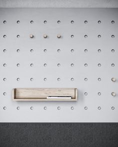 a wall mounted shelf with several holes on it and a pen in the bottom right corner