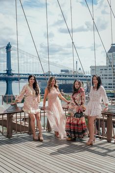 three beautiful women standing on the side of a bridge