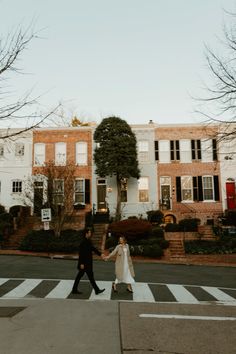 two people walking across a street holding hands