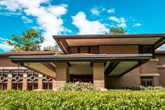 the exterior of a modern house with green hedges and blue sky