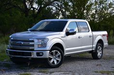 a silver truck parked on top of a gravel road