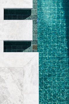 an aerial view of a swimming pool with blue water and white tiles on the sides