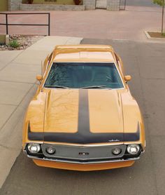 an orange and black muscle car parked on the street