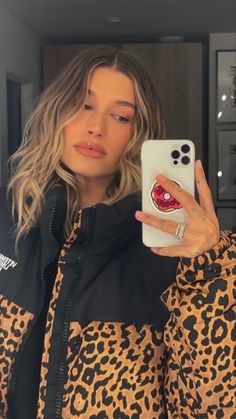 a woman taking a selfie with her cell phone in front of her face and wearing an animal print jacket