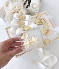 a person is holding onto some gold and white decorations on a table with other items in the background