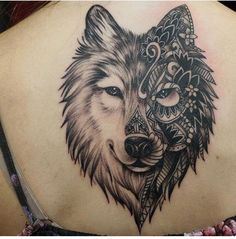 a woman's back with a wolf tattoo on her shoulder and an intricate design