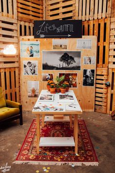 a table with pictures and plants on it in a room filled with wooden pallets