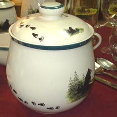 a white tea pot sitting on top of a table next to glasses and silverware