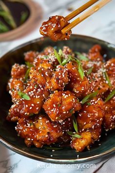 a black plate topped with fried chicken and chopsticks