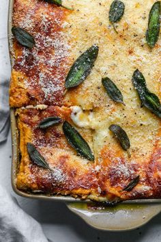 a casserole dish with cheese and sage leaves on top, covered in powdered sugar