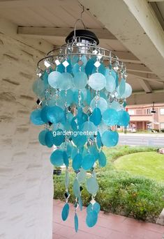 a blue chandelier hanging from the side of a white building with green grass in the background