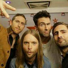 four men posing for the camera with one pointing at them