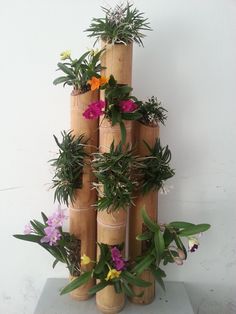 there is a tall tower made out of bamboo sticks with flowers on each side and greenery in the middle